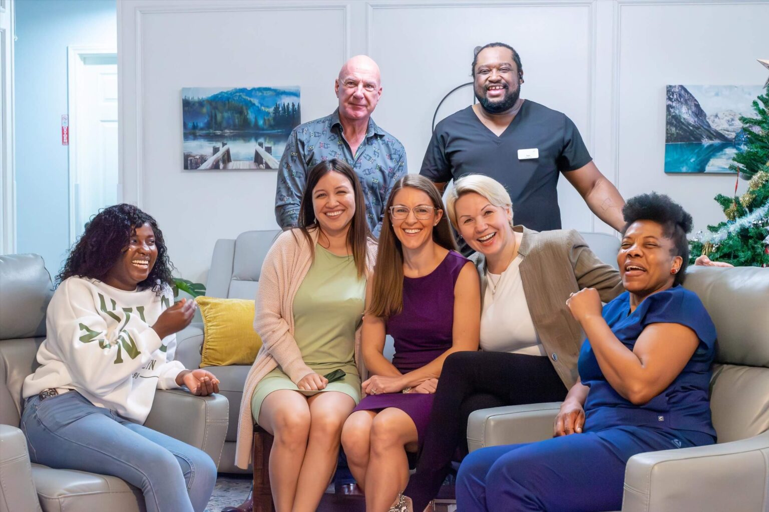 Smiling Our Cottage community members gathered together in a bright lounge area