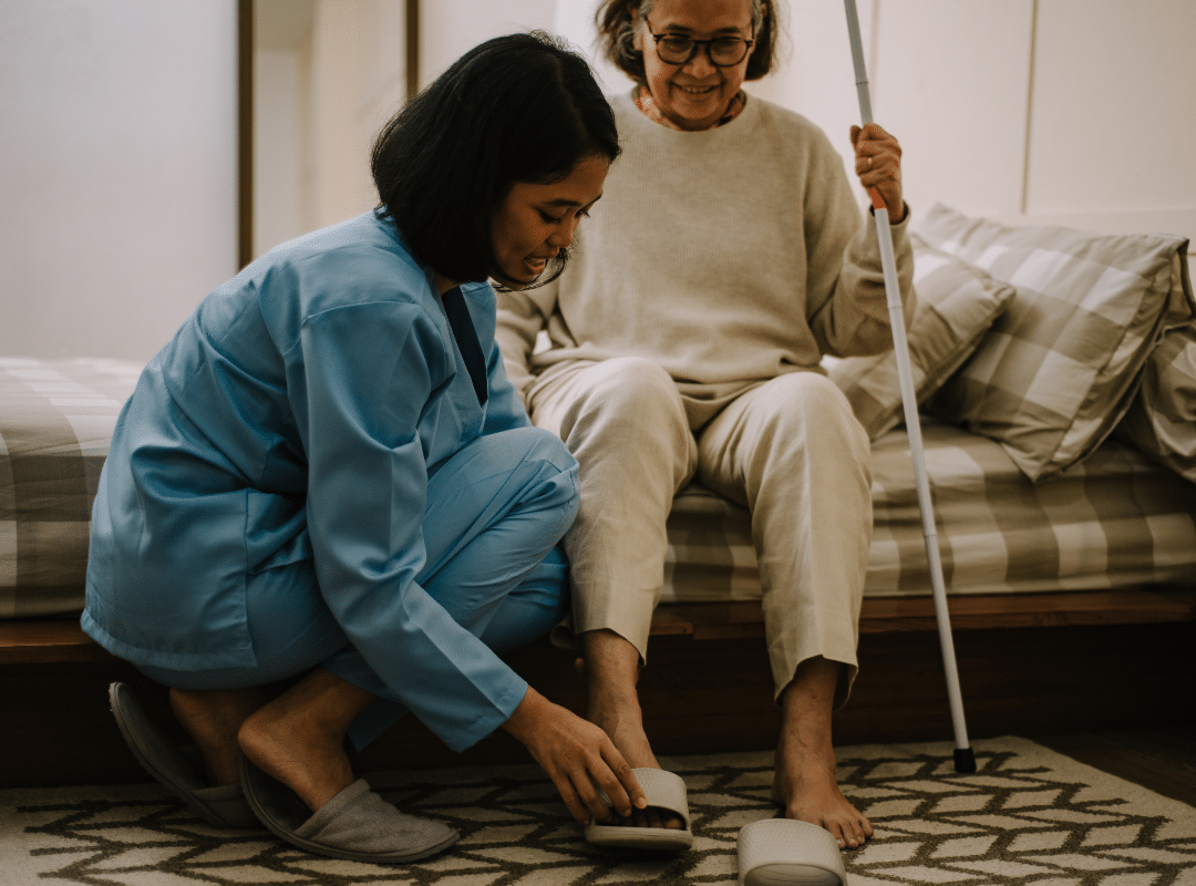 A woman assists an elderly woman using a cane